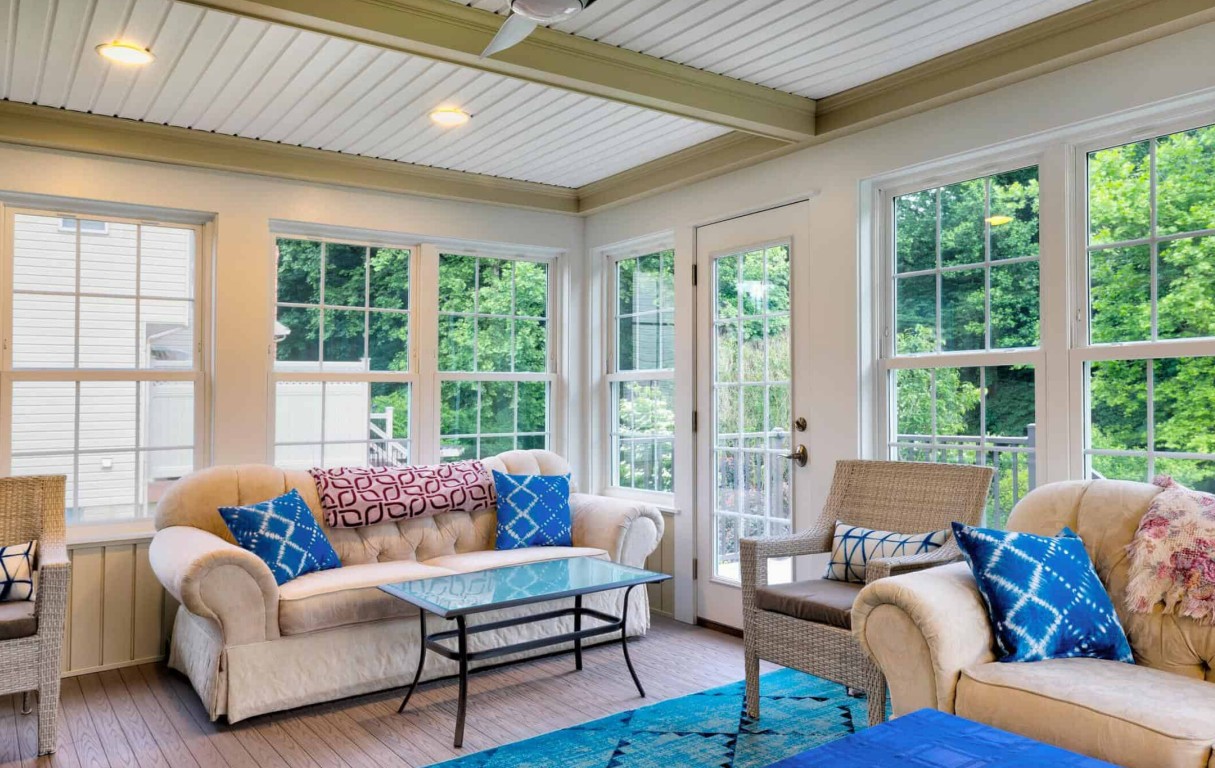 Bright traditional sunroom with multiple windows and beige furniture